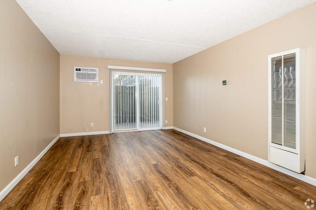 the spacious living room of an apartment with wood flooring and sliding glass doors at Ella 1711 Apartments, Woodland California