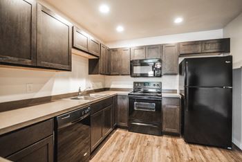 a kitchen with black appliances and wooden cabinets at Madison Park, Bozeman, MT, 59718