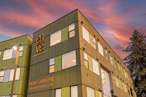 A modern building with the words "enve" and "Now Leasing" on its side.