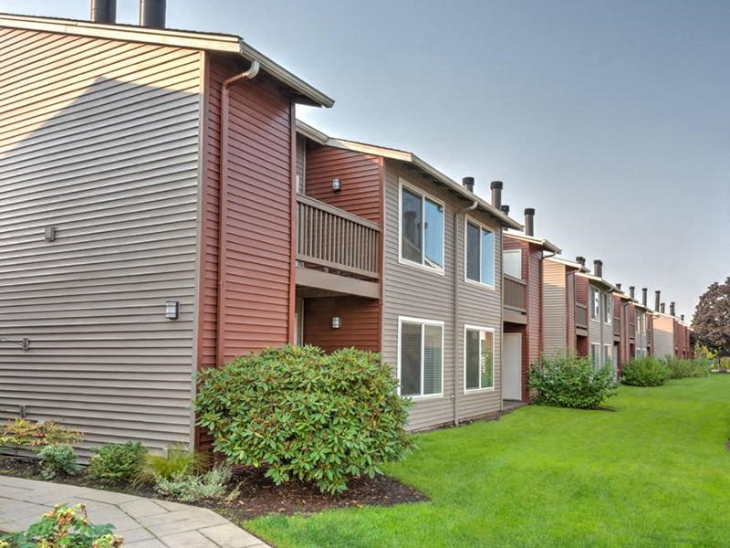 Outside of apartments with patios and balconies. Lined with manicured green lawn and landscaping. at Pointe East, Fife, Washington