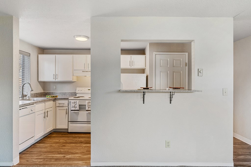Kitchen divided by a wall with looking window and a small counter. Behind the wall is a pantry door next to a white fridge.at Capitol Crossing, Olympia