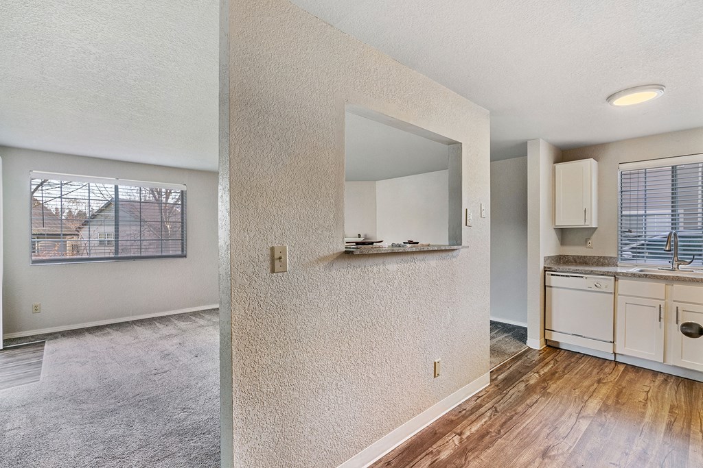 Living room and wood floor kitchen divided by a textured wall, large windows with blinds in living and kitchen area.at Capitol Crossing, Washington