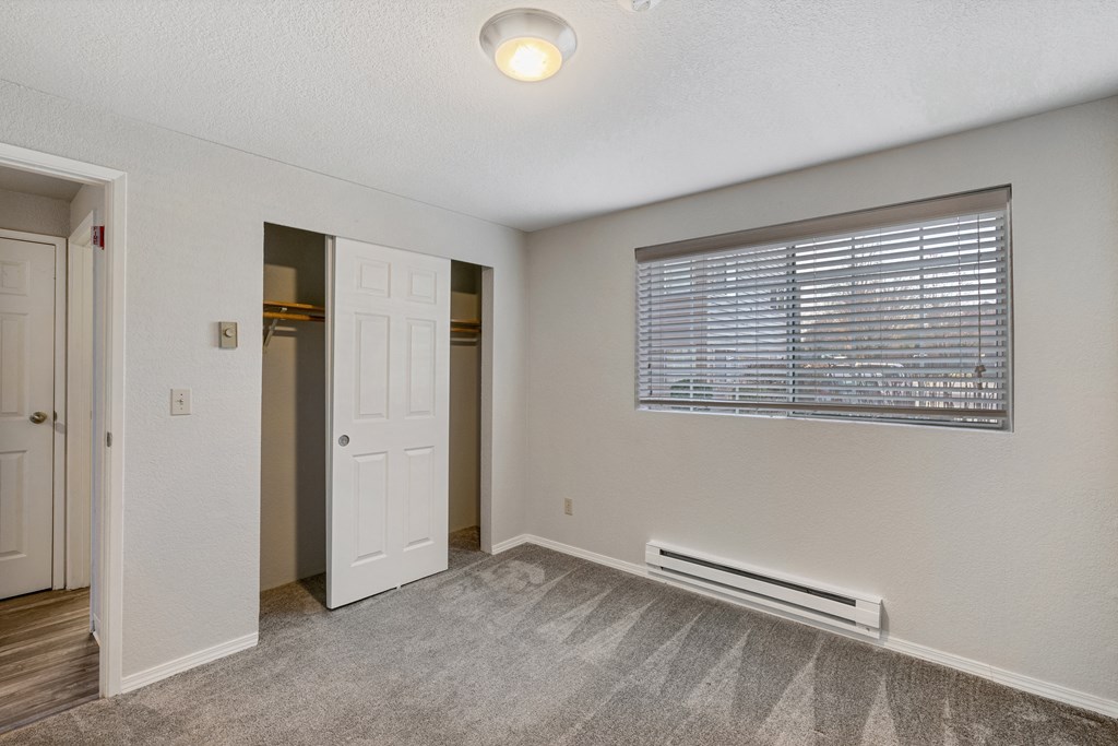 an empty bedroom with a window and a door to a closet