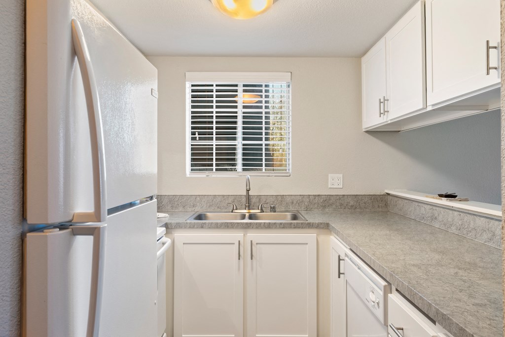 a kitchen with white cabinets and a sink and a refrigerator
