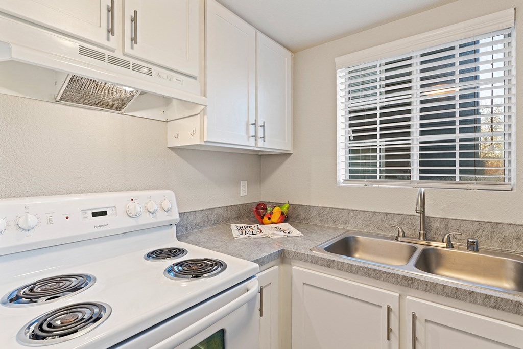 Kitchen corner staged with fruit bowl and hand towels. White stove, range hood, and stainless steel sink.at Capitol Crossing, Washington