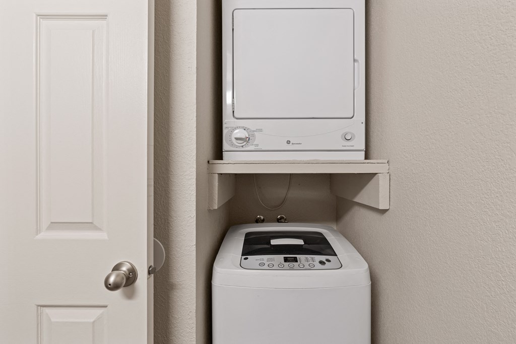 a small laundry room with a washer and dryer and a white door