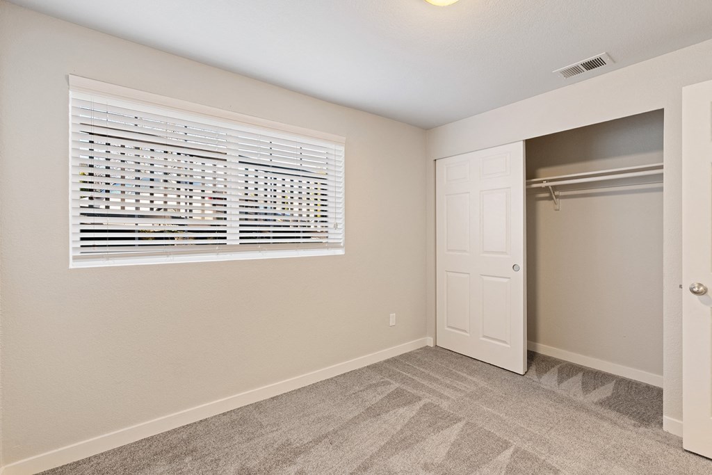 Carpeted bedroom, window with white blinds, and large sliding door closet with closet rod.at Capitol Crossing, Washington, 98501