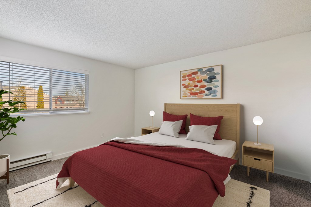 Bedroom with taupe carpet, white walls, and a large window with blinds. Staged with a queen-size bed, 2 side tables, a rug, and art. at Pointe East, Washington