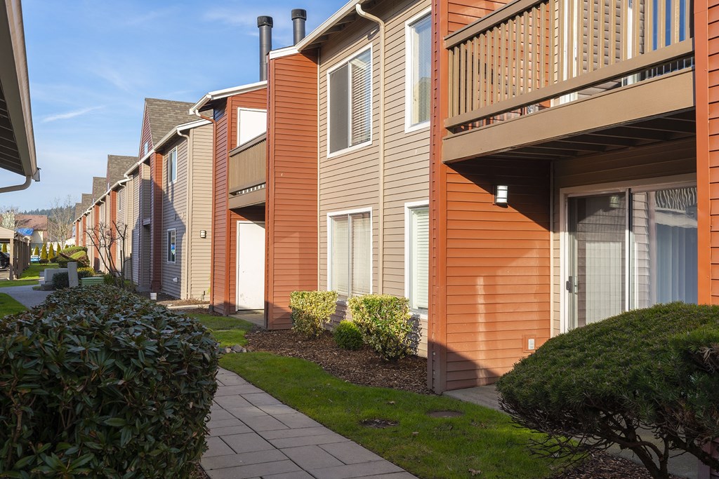 Exterior view of orange and tan apartments with balconies and patios at Pointe East in Fife, WA.