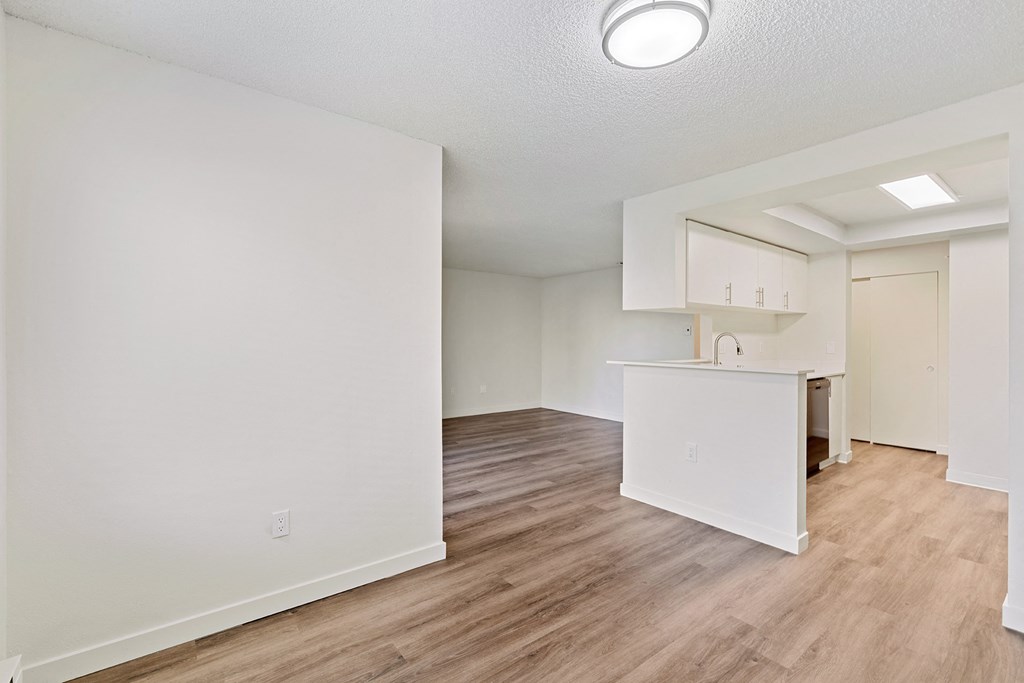 Open layout apartment with wood flooring and white walls at Pointe East Apartments in Fife, WA.