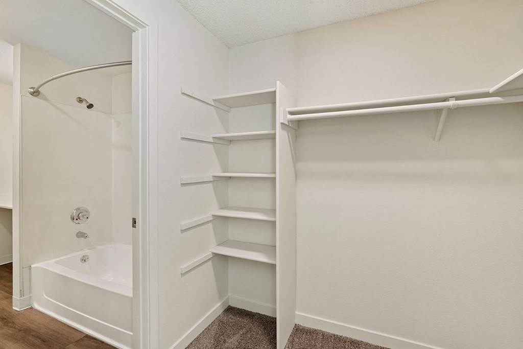 A walk-in closet with custom shelving and access to the bathroom on the left. at Pointe East, Fife, WA, 98424