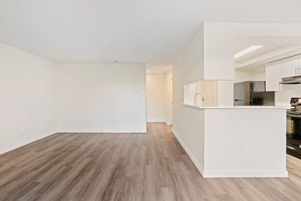 A spacious living room with wood flooring and the kitchen with a large breakfast bar to the right. at Pointe East, Fife, WA, 98424