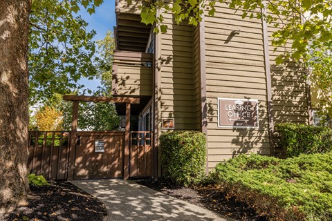 A leasing office is located in a building with a brown fence and greenery around it.