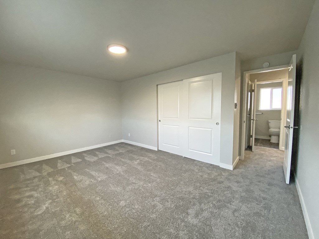 Carpeted bedroom, huge closet at Quilceda Gardens, Washington, 98270  with sliding doors, door to the hallway, and bathroom.