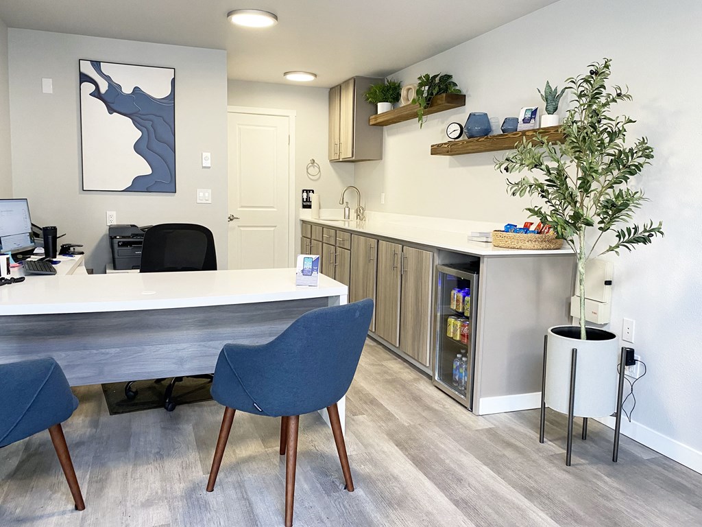 The Trail Apartments lobby office with a l-shaped desk, 2 blue chairs, and a mini fridge with drinks and snacks.at The Trail, Snohomish, WA