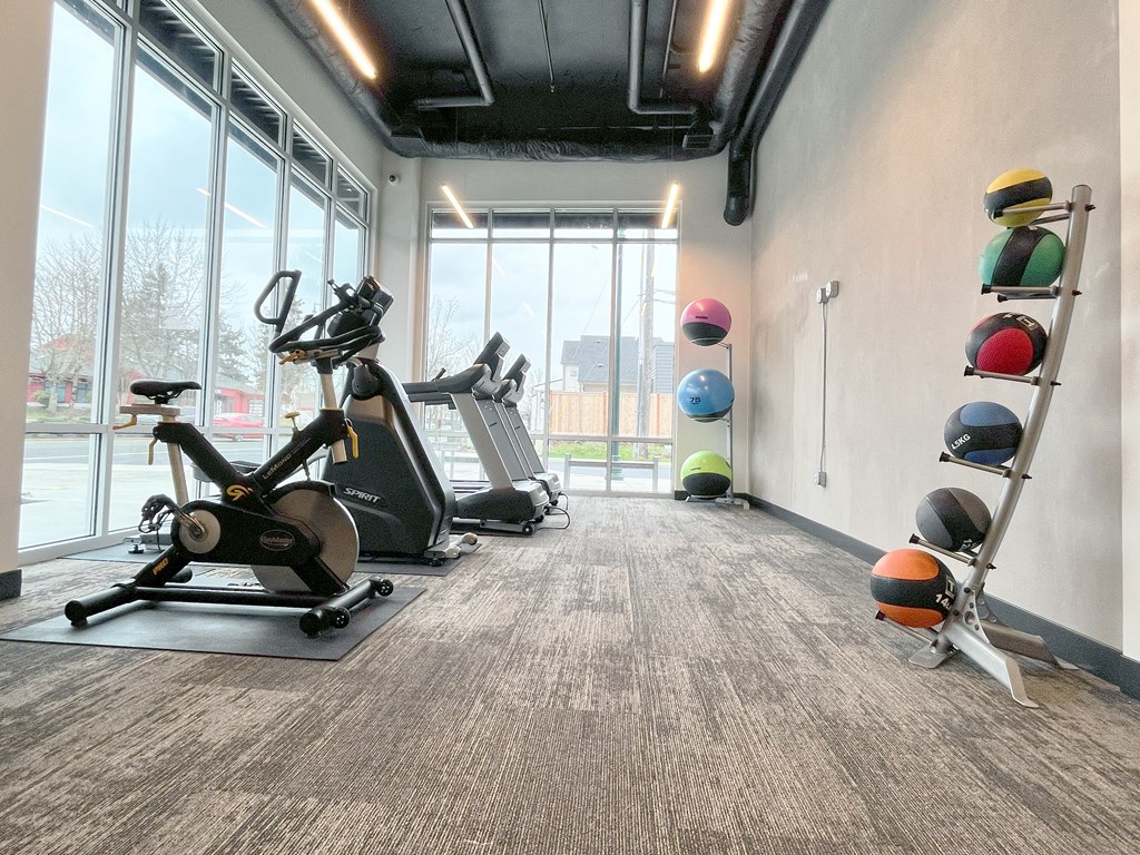 a gym with treadmills and weights at the district at highland village apartments at The Duo, University Place, WA 98466