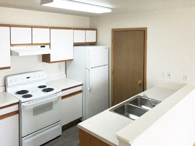 A kitchen with a white stove, white refrigerator, and a white countertop.