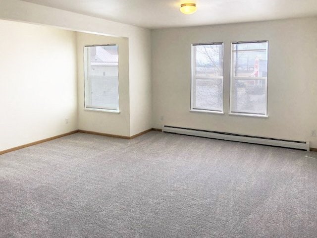 A room with a carpeted floor and two windows.