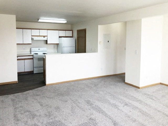 A kitchen with white cabinets and appliances is visible through a doorway.