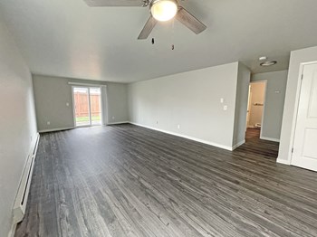 Open layout living room with ceiling fan and sliding glass doors on the back wall to private fenced-in patio. - Photo Gallery 26