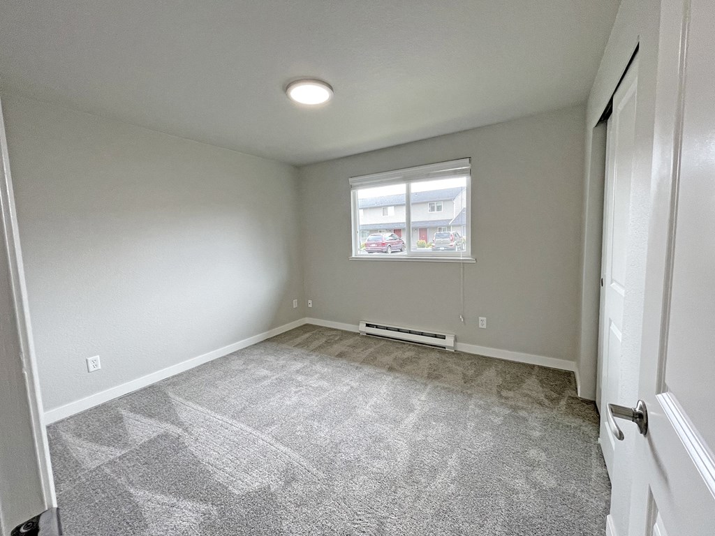 Bedroom with gray carpet, window with white blinds on the back wall, on right wall double sliding door closet.at Quilceda Gardens, Marysville, 98270