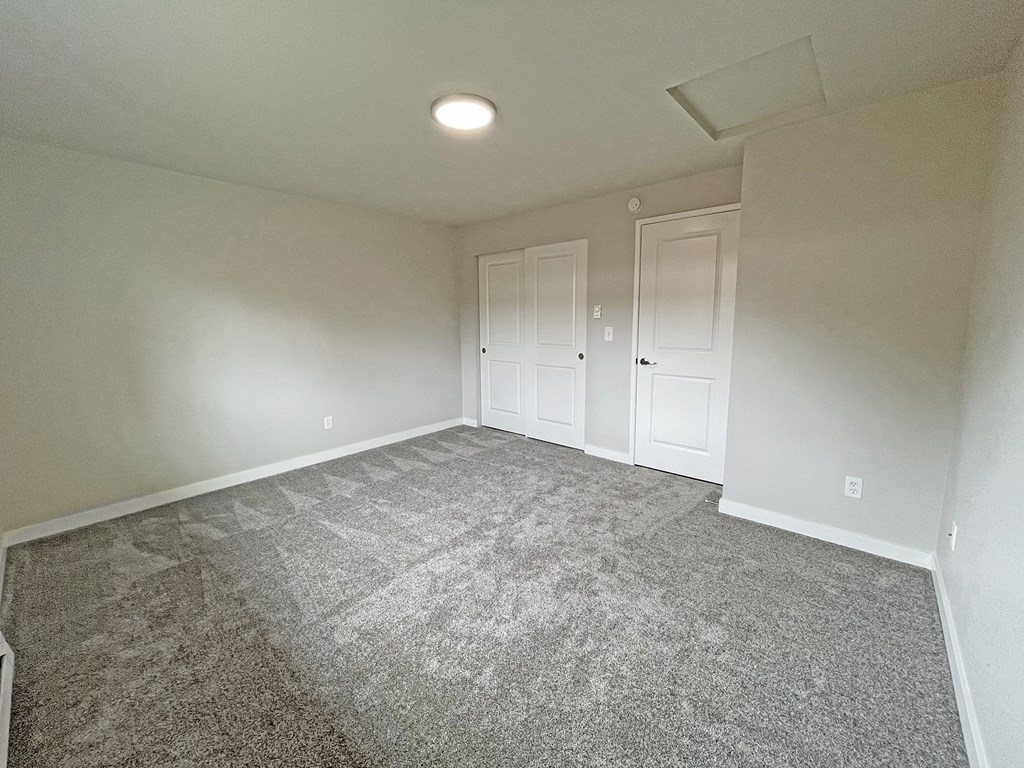 Large carpeted bedroom with double sliding door closet on the back wall next to the bedroom door.at Quilceda Gardens, Marysville, Washington