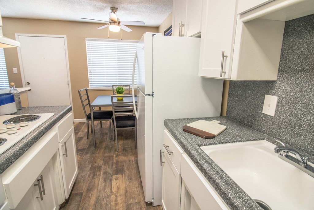 Galley kitchen with new white cabinets and gray faux granite countertops, with dining area visible in the distance Galley kitchen with new white cabinets and gray faux granite countertops, with dining area visible in the distance at Woodland Village , California, 95695