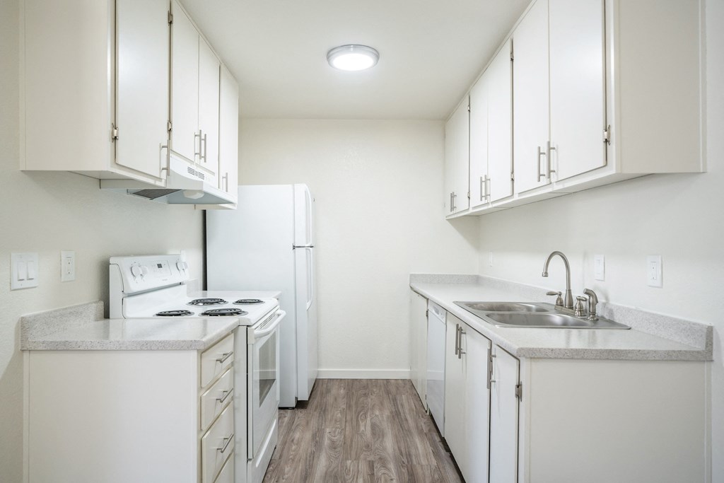 an empty kitchen with white appliances and white cabinets at Kirkwood Meadows Apartments in Pocatello, ID