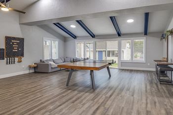 Spacious clubhouse with a ping pong table, games, and a large sectional couch.