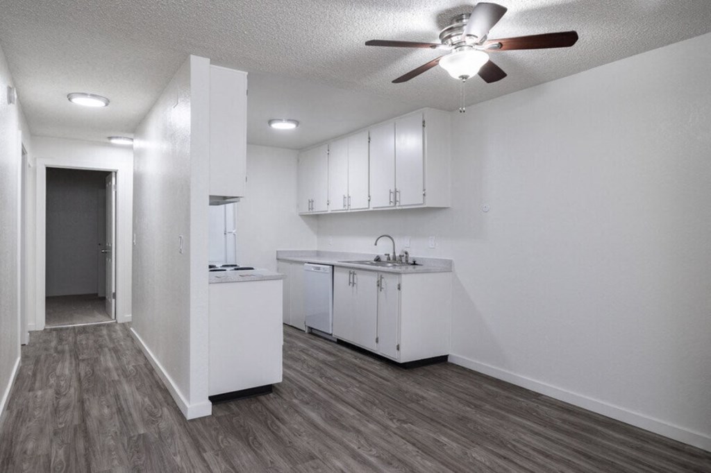 an empty kitchen with white cabinets and a ceiling fan  at Kirkwood Meadows, Pocatello
