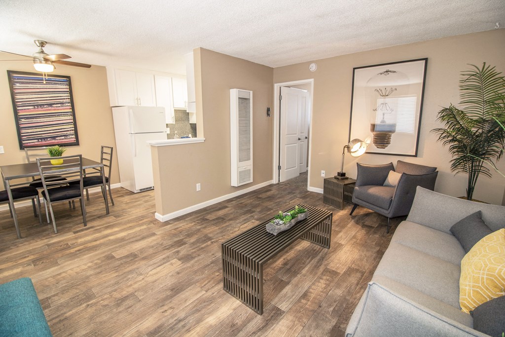 Living room that flows into dining area, staged with couch, chair, two tables, lamps and plants.at Woodland Village , California, 95695