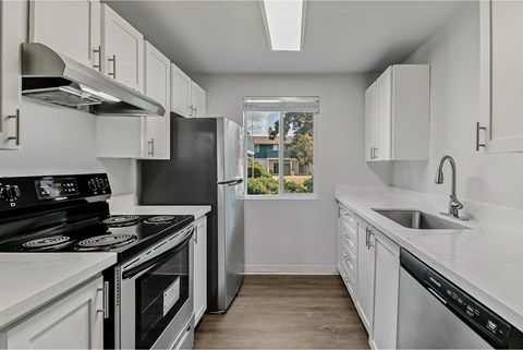 A kitchen with white cabinets and black appliances.