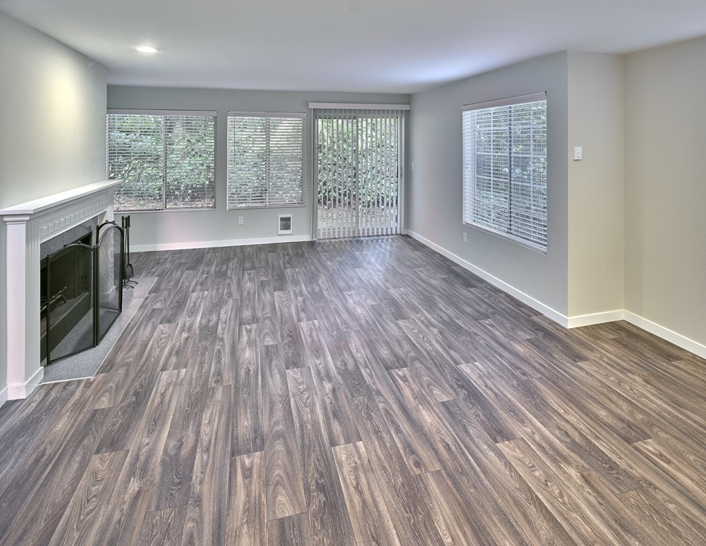 an empty living room with a fireplace and wooden floors at Edmonds Gateway, Washington
