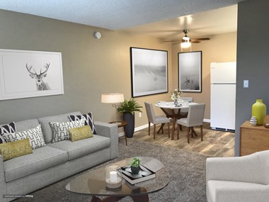 Living room with dining room visible in the background.  There is a couch, chair, and coffee table in the living room with a round dining table and ceiling fan above.