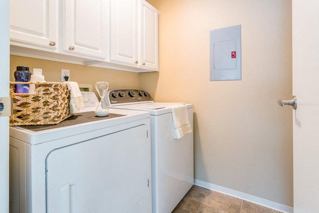 a washer and dryer in a laundry room with white cabinets  at Springfield, Renton, WA