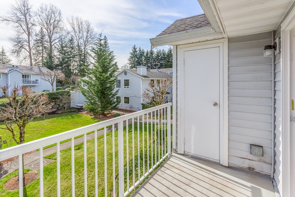 the view of the yard from the balcony of a home with a white door  at Springfield, Renton, WA, 98055