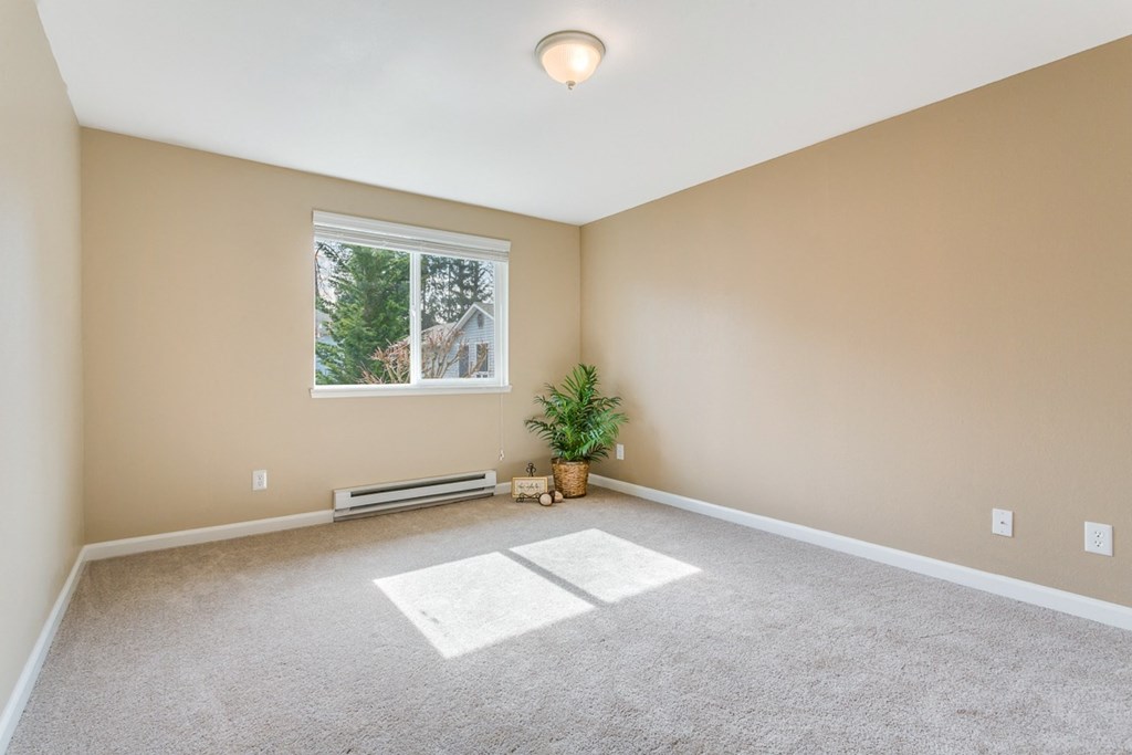 an empty living room with carpet and a window  at Springfield, Renton, WA