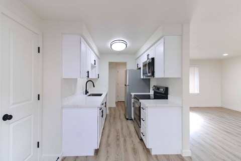 A kitchen with white cabinets and a black fridge.