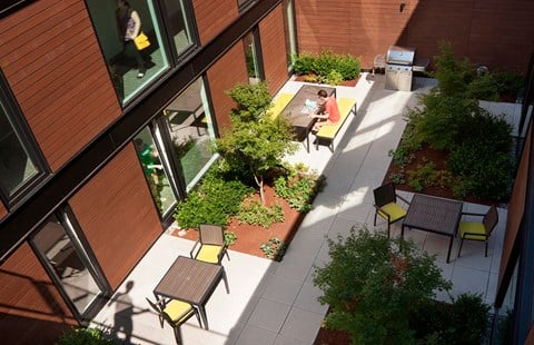 Exterior view of community. Beautiful landscaping with seating areas, a community grill and pathways to the building.at 19th & Mercer, Seattle