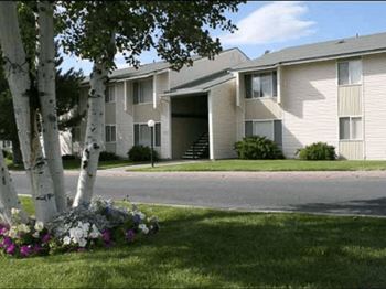 A street view of Kirkwood Meadows Apartments with flower and trees and blue skies in the background.at Kirkwood Meadows, Pocatello, ID 83201