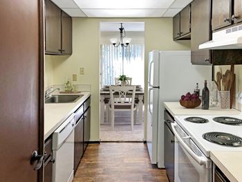 a galley-style kitchen with white appliances, top and bottom cabinets and a view to the dining room.at Castlerock, Wenatchee