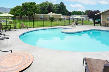 a resort style pool with chairs and tables and a fence around it at Park View Apartments, Wenatchee, 98801