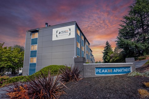 The image shows a building with the sign "Peak88 Apartments" in front of it.
