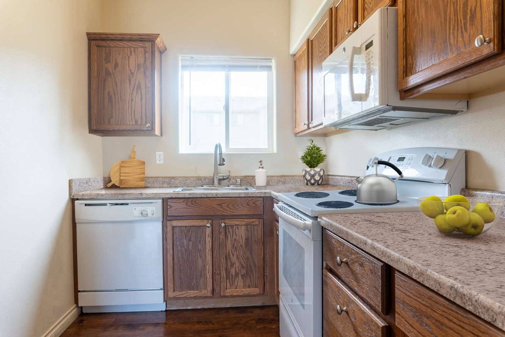 Kitchen L-shaped kitchen with wood cabinets top and bottom, dishwasher, sink with window above, oven, stovetop, microwave. at Pine Tree Park, Washington, 99337