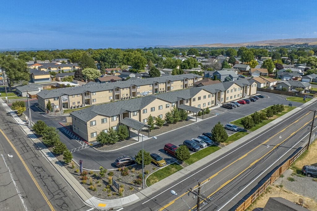an aerial view of an apartment complex with cars parked on the street