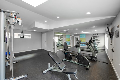 A gym with a row of treadmills and a weight machine.