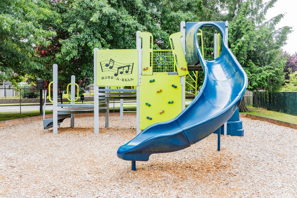A blue slide in a playground with a yellow and black sign.