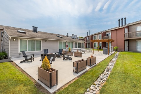 A sunny day at a residential complex with a well-maintained lawn and outdoor furniture.