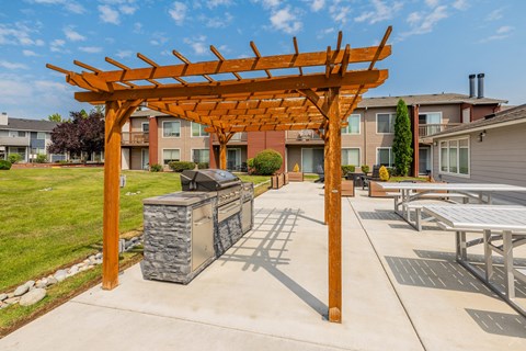A wooden pergola is in the middle of a concrete patio.