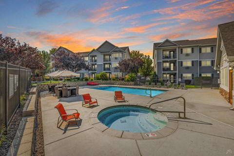 A swimming pool surrounded by chairs and a building in the background.